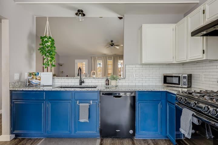 Kitchen with blue lower cabinets, white subway tile backsplash, granite counters, and black appliances.