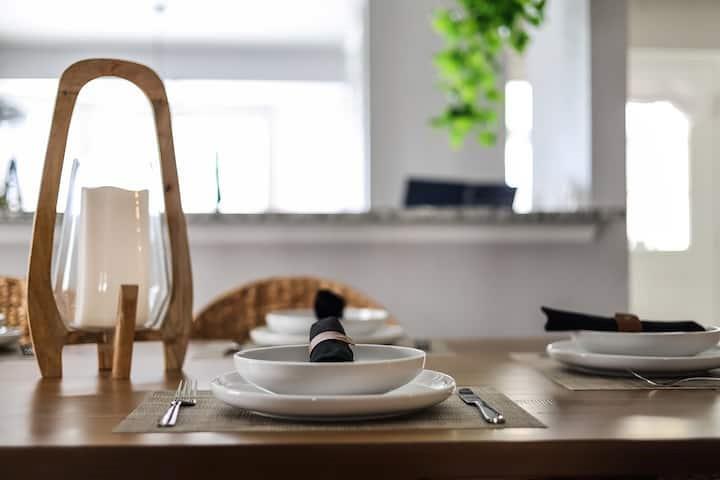 Staged dining table with white place settings and a wooden candle lantern.