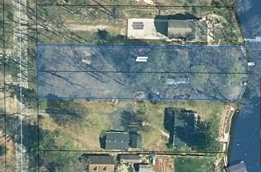 Aerial view of a wooded parcel outlined in blue beside a body of water.
