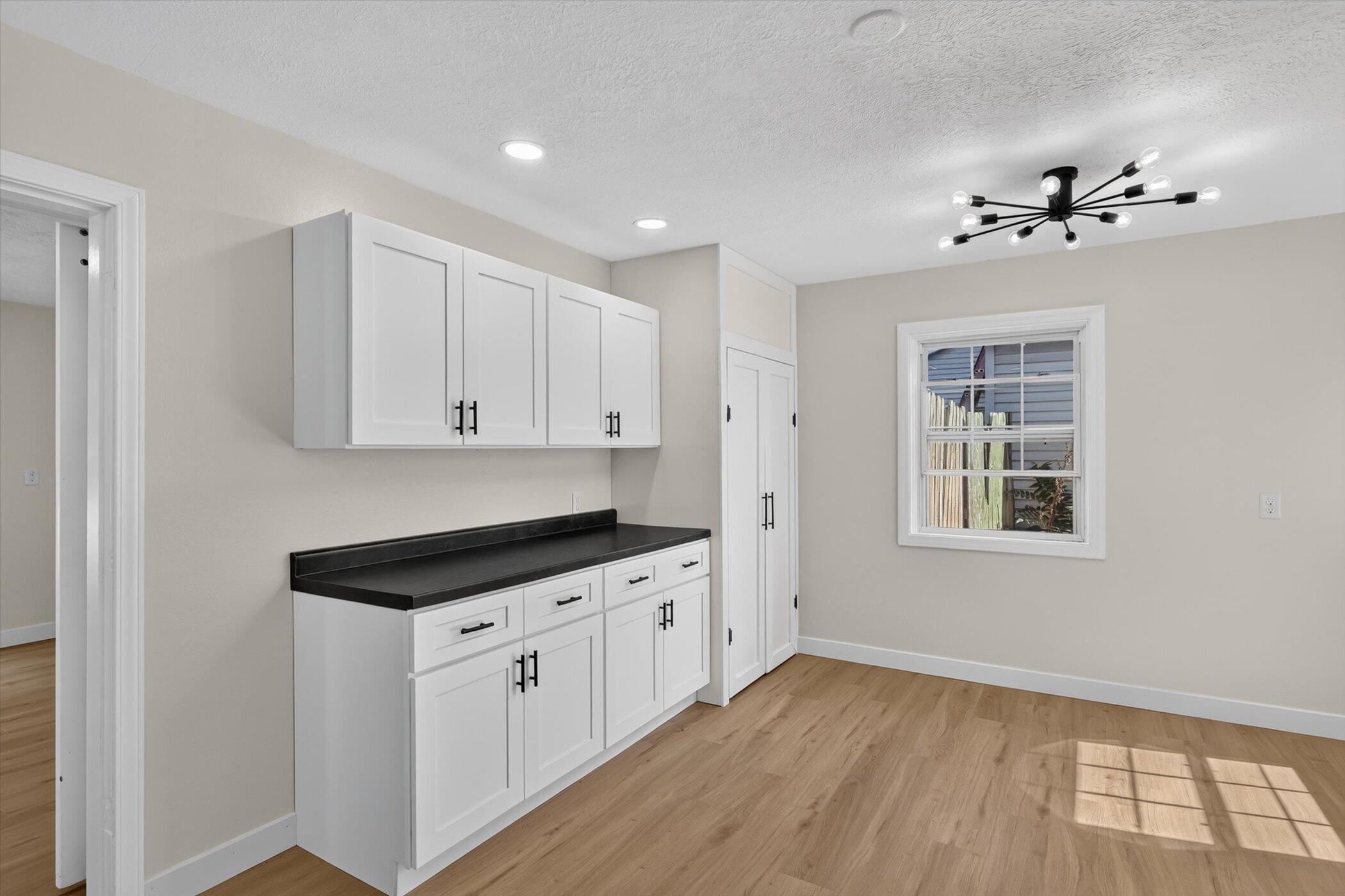Kitchen with white shaker cabinets, black countertops, and a modern starburst ceiling light.