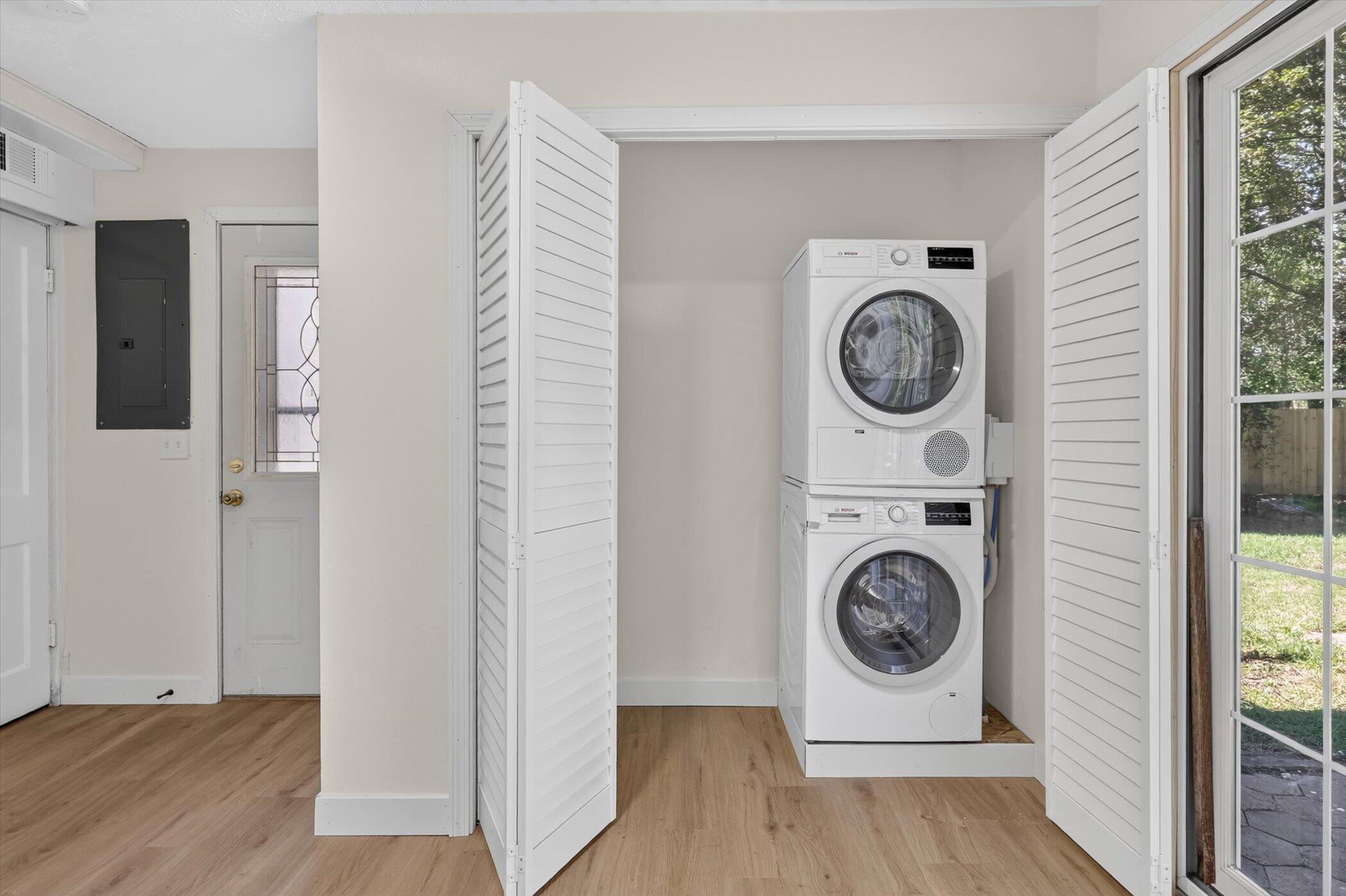 Laundry area with stacked washer and dryer behind open louvered doors.