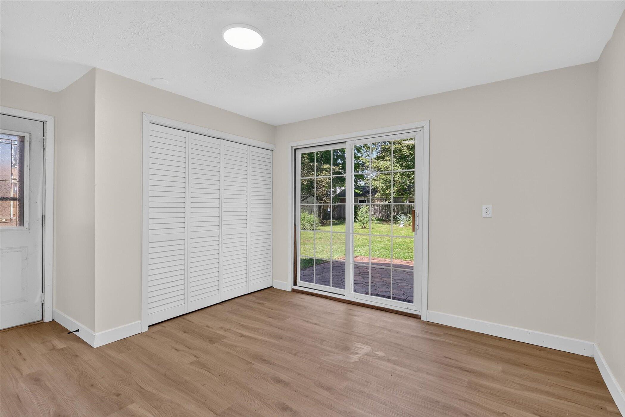Empty room with louvered closet doors and a sliding glass door to the patio.