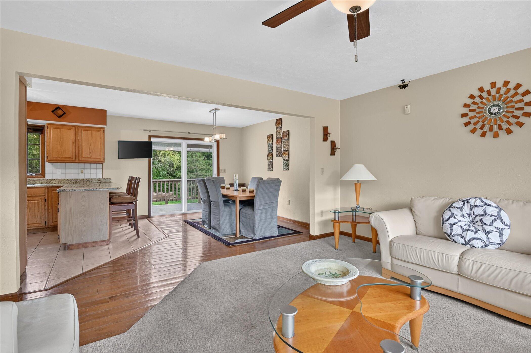 Furnished living room with adjoining dining area, kitchen, and sliding doors to a deck.