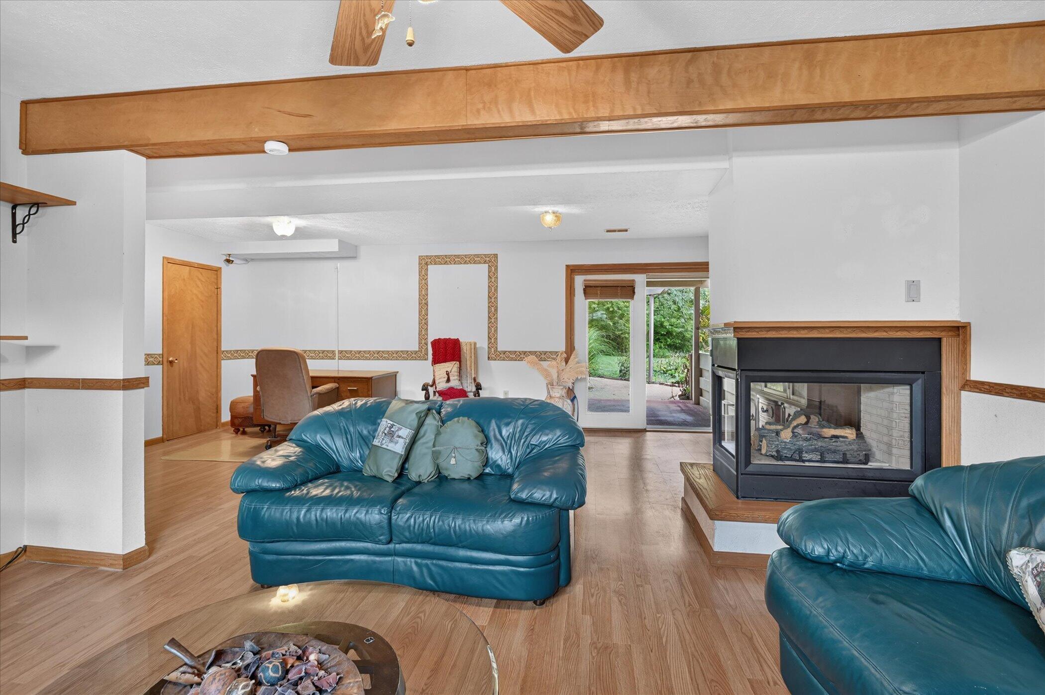 Living room with teal leather sofas, a wood-trimmed corner fireplace, and sliding glass doors to the garden.