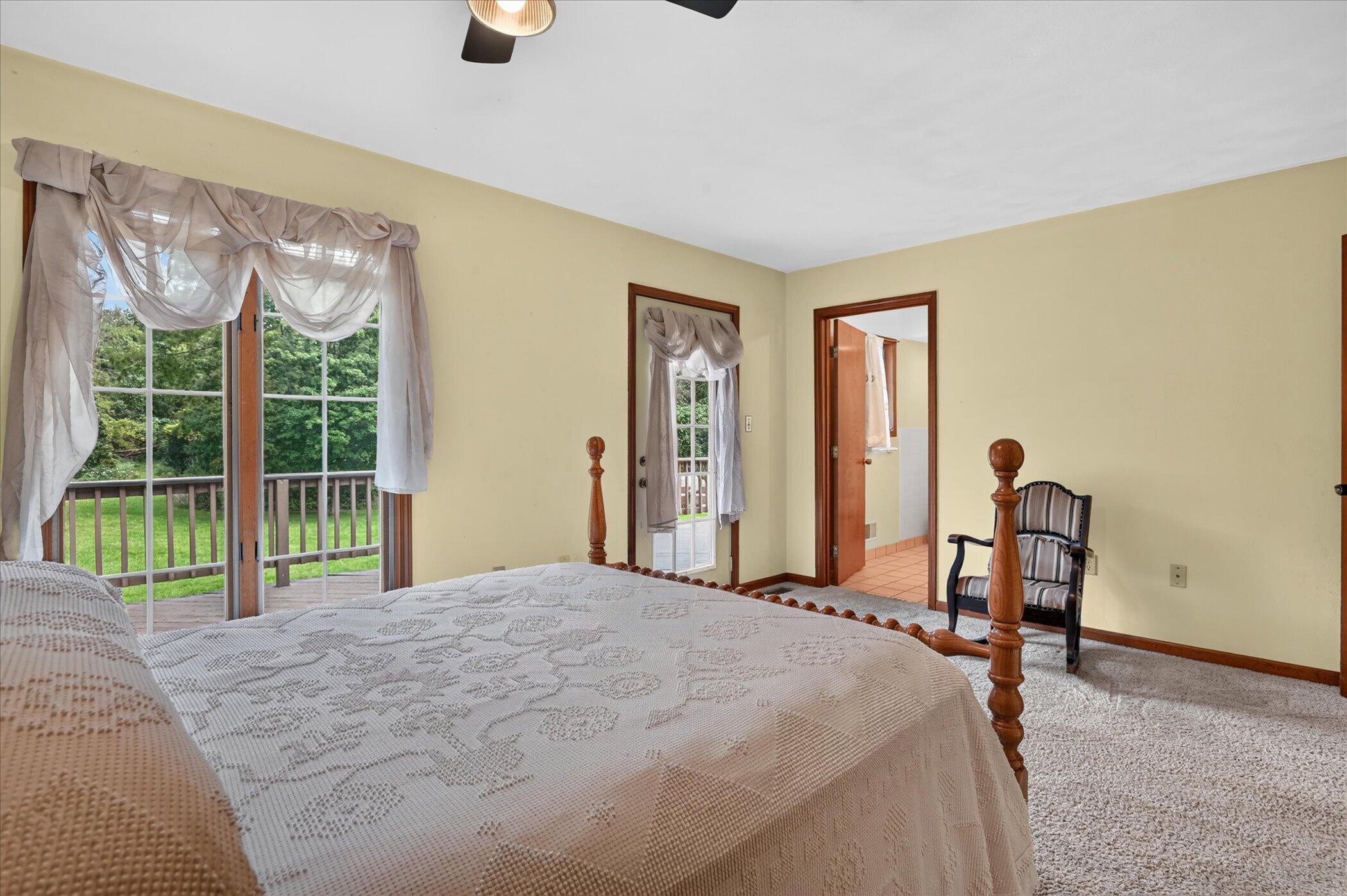 Bedroom with a large bed and sliding glass doors opening onto a deck and green yard.