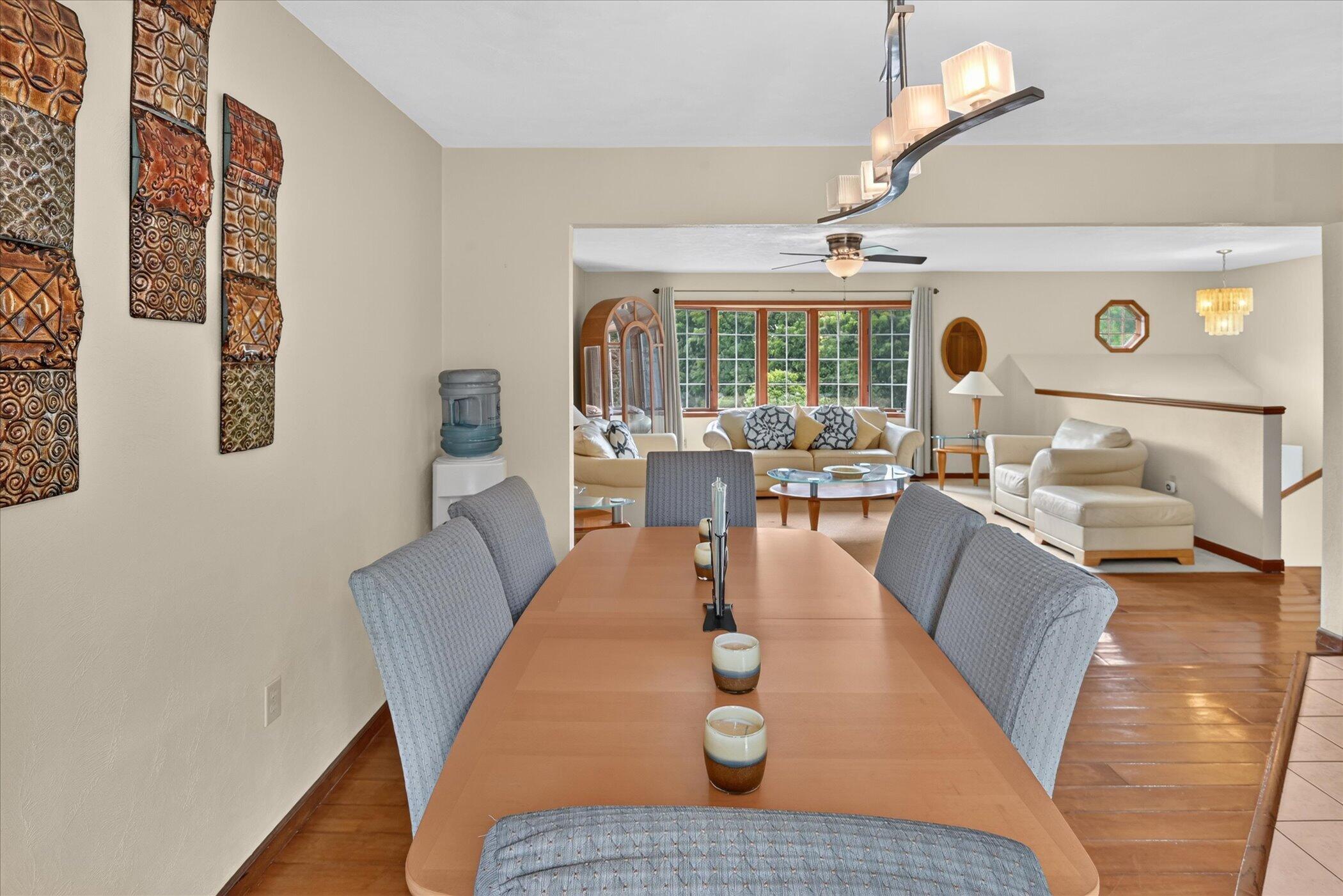 Dining room with a long wooden table opening onto a bright living room with large windows.