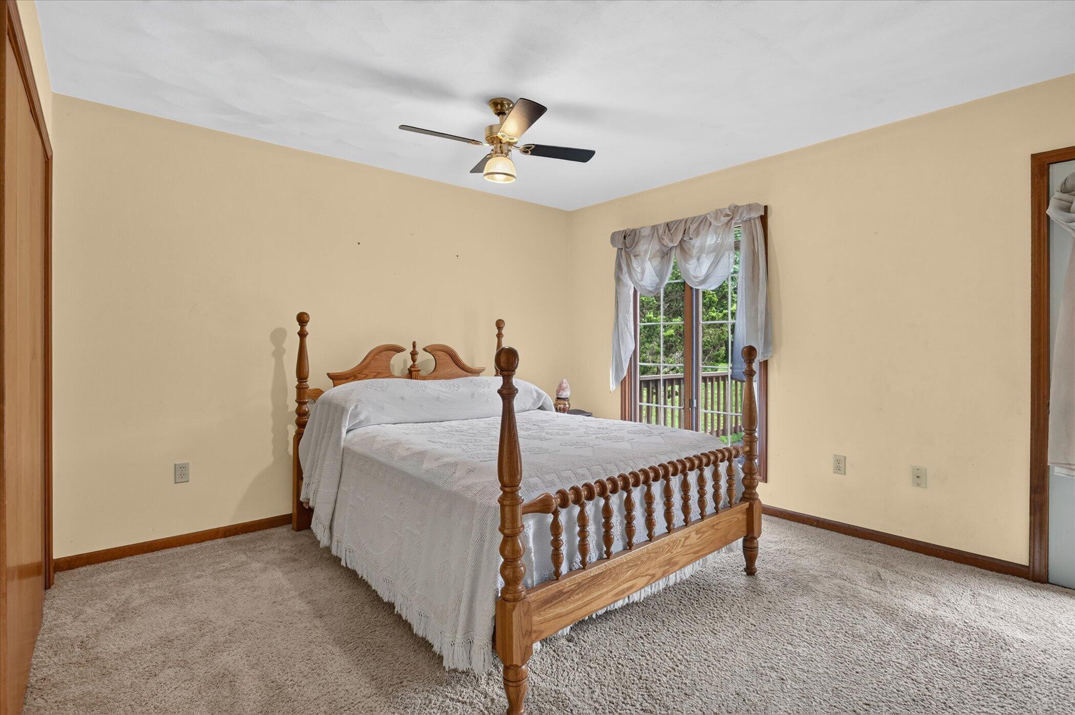 Bedroom with a carved wooden four-poster bed and a curtained glass door to the deck.
