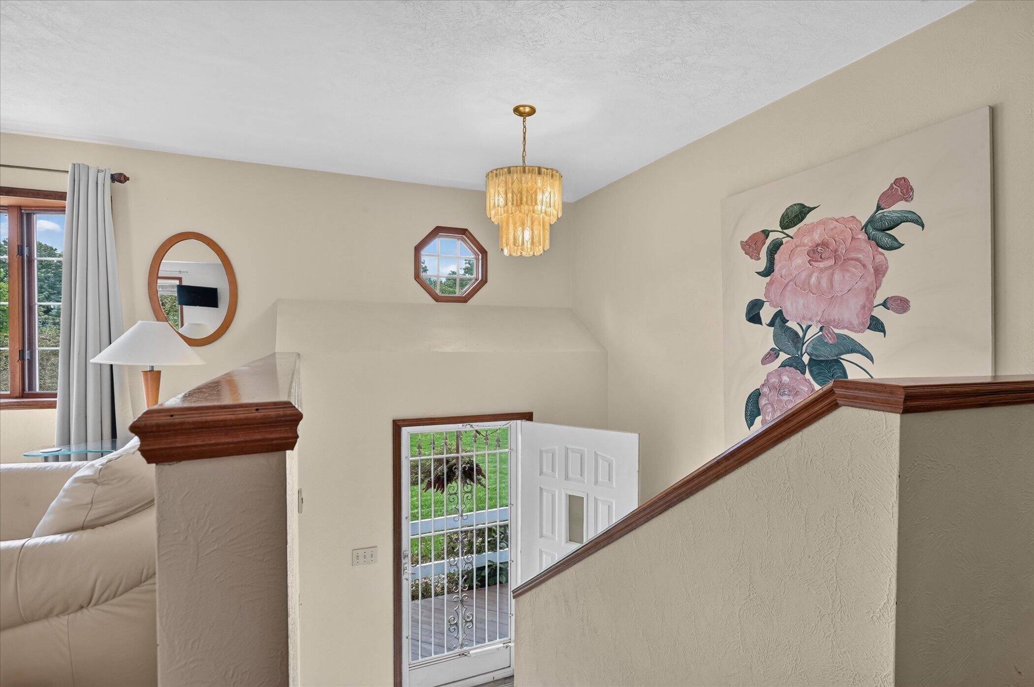 Foyer landing overlooking an open front door, with dark wood stair rails and large floral wall art.