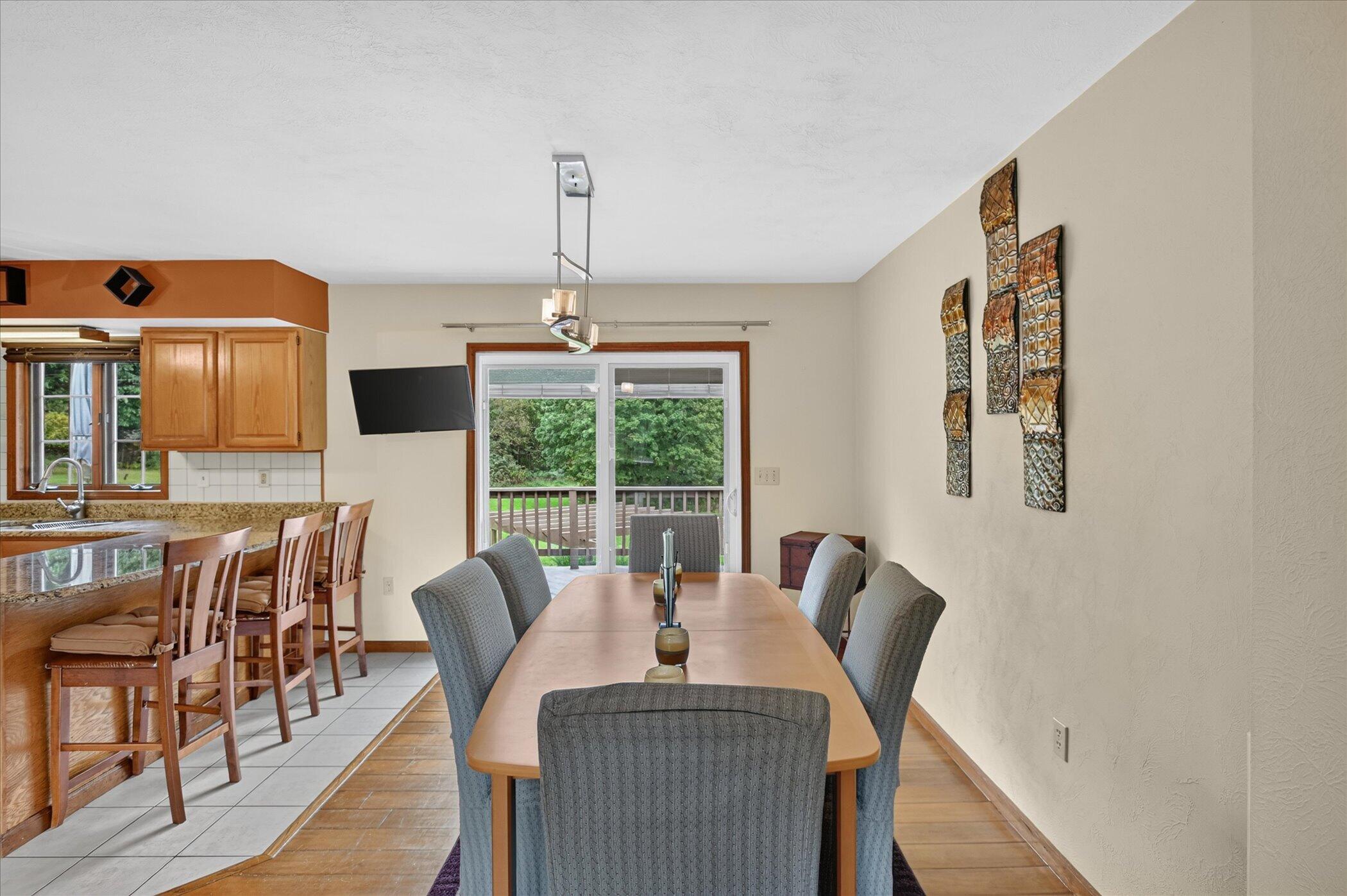 Dining room with a long table beside the kitchen and sliding doors to a deck.