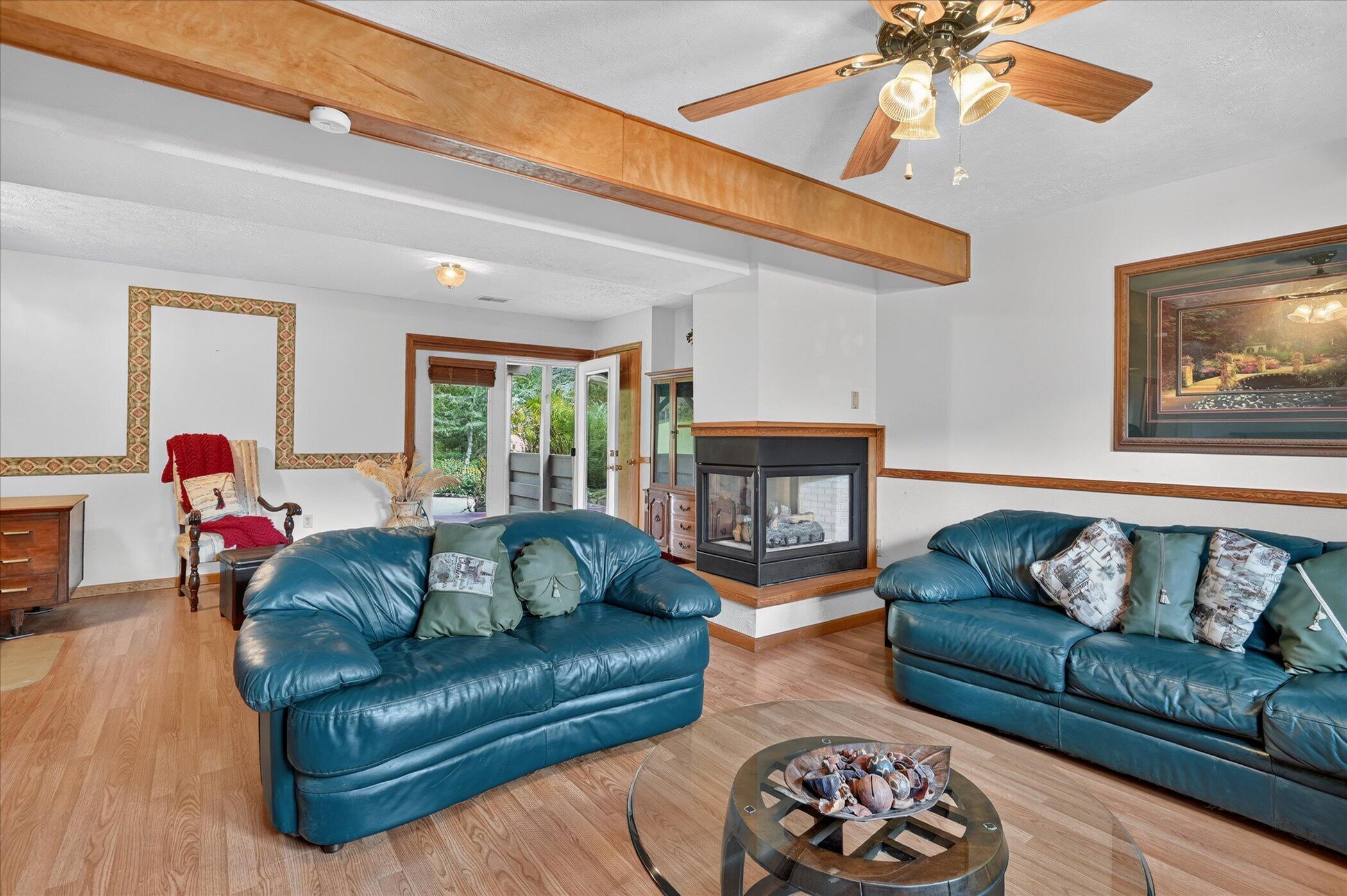 Living room with blue leather sofas, a corner fireplace, and a broad wood ceiling beam.