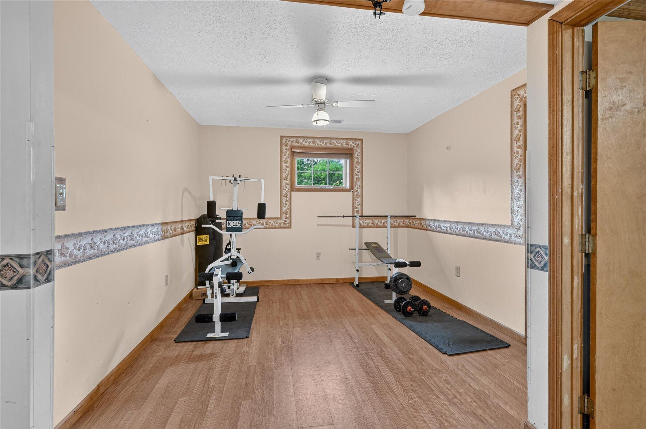 Home gym with weight machine, bench, and dumbbells on exercise mats.