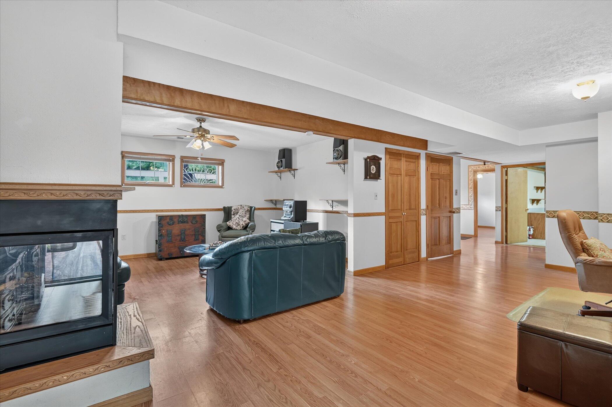 Furnished living room with a black fireplace, leather seating, wood-look floors, and a ceiling beam.