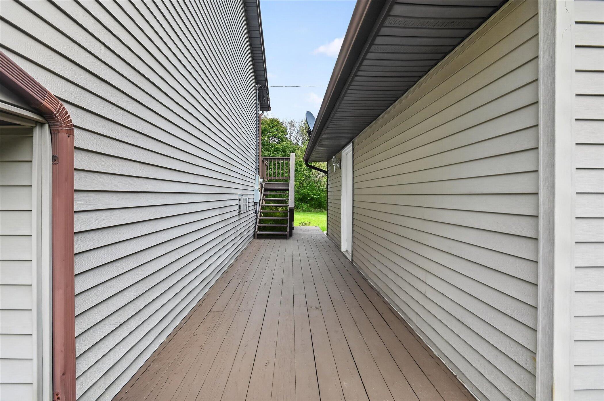 Narrow deck between two house walls, with stairs leading to a raised landing.
