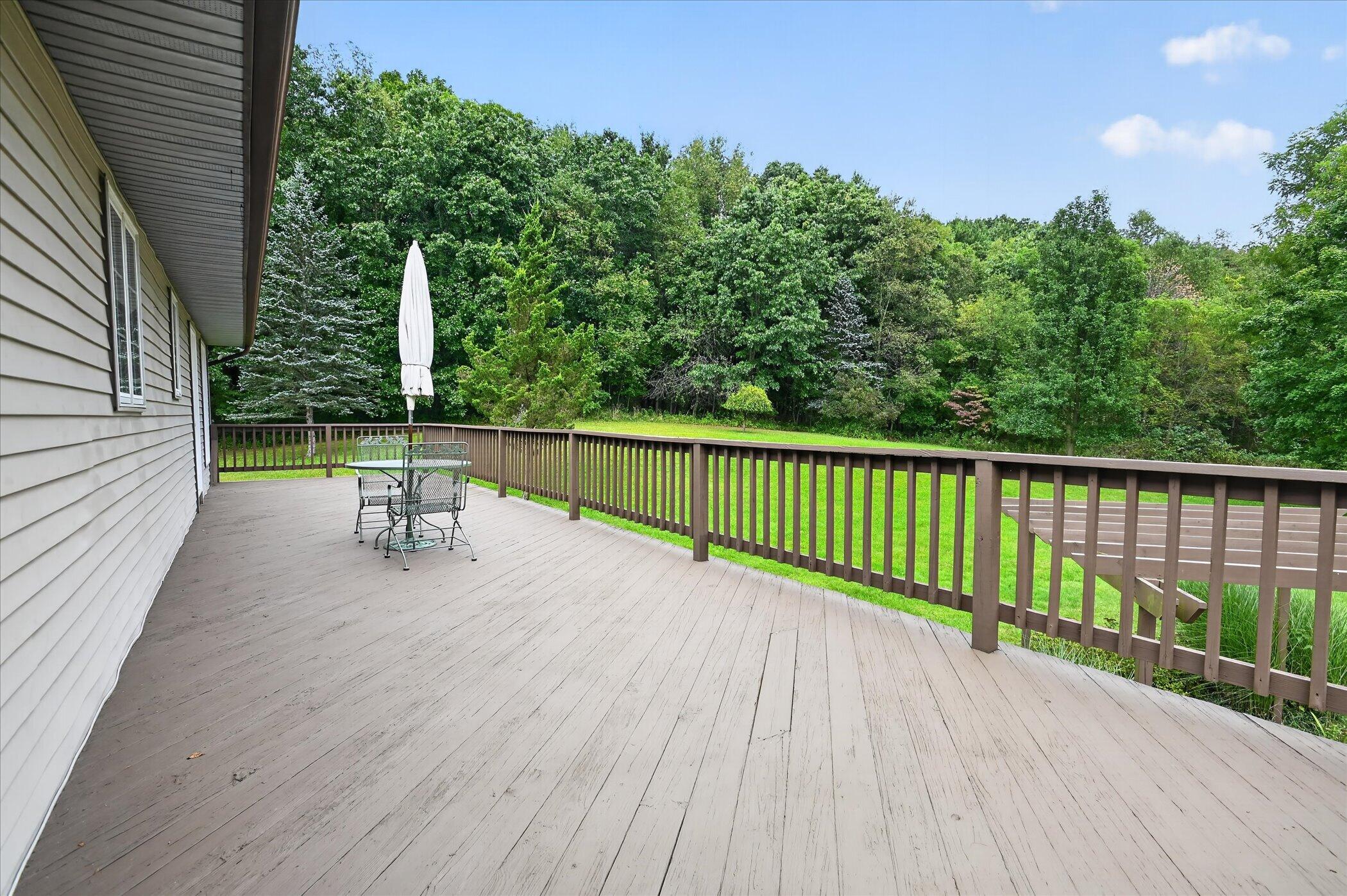 Raised deck with a metal patio set, overlooking a green lawn and wooded yard.