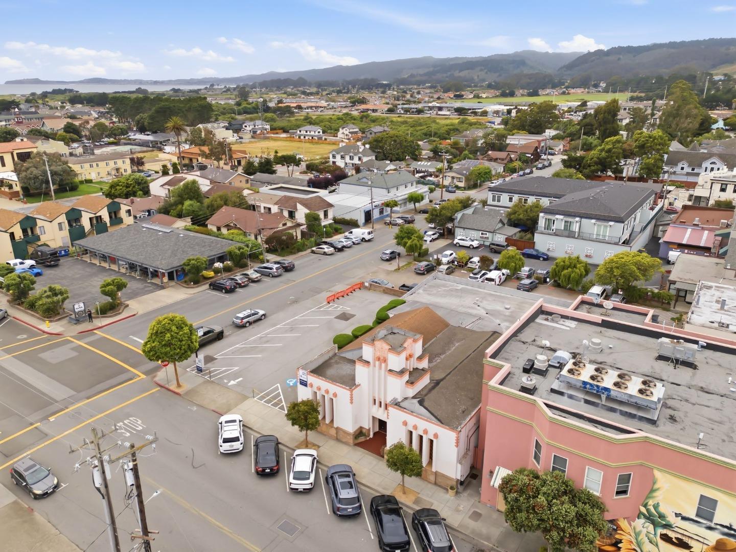 Aerial view of a coastal neighborhood with distant hills and water on the horizon.