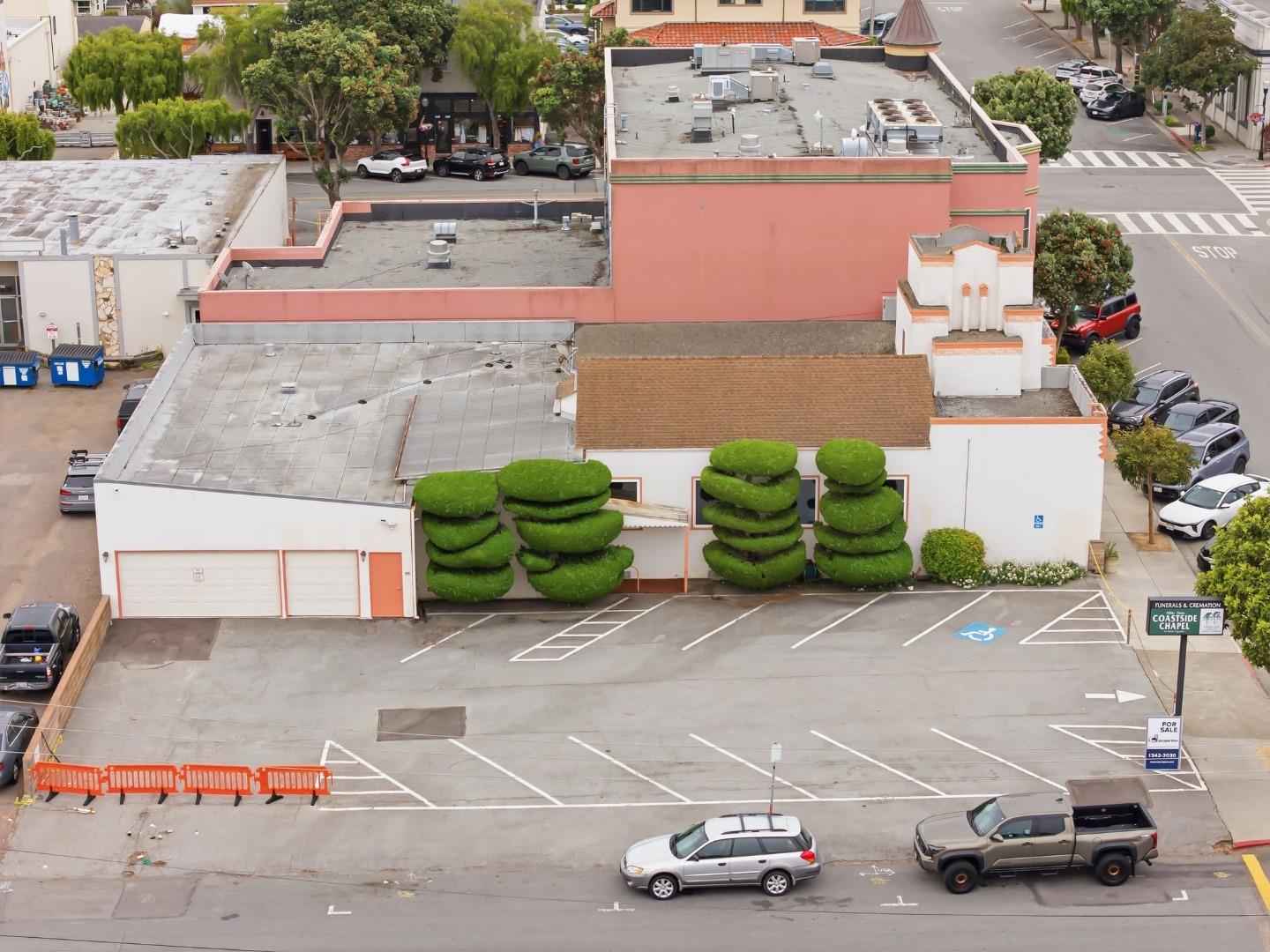 Aerial view of a white chapel with sculpted hedges and a large parking lot.