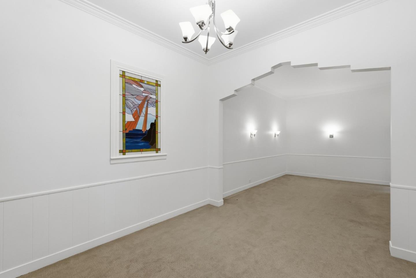 Empty carpeted room with a stepped archway and colorful stained-glass window.