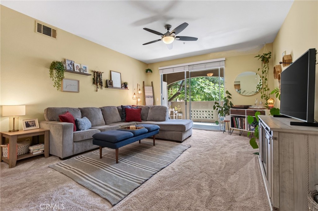 Furnished living room with a gray sectional, sliding glass doors, and leafy outdoor views.