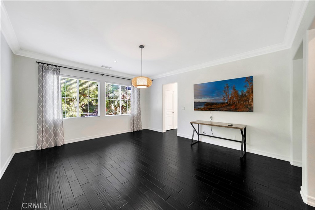 Dining room with dark flooring, large curtained windows, and a console table beneath landscape art.