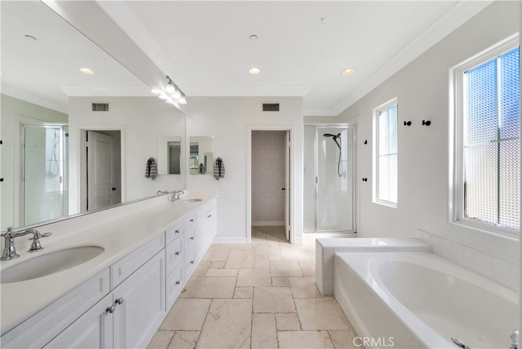 Bright bathroom with a double-sink vanity, soaking tub, and separate glass shower.