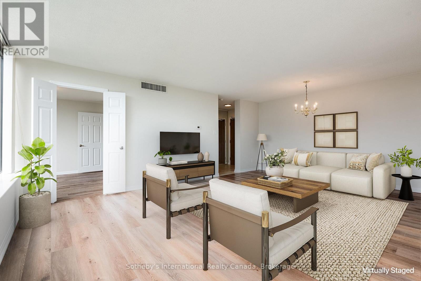 Virtually staged condo living room with a cream sectional, two armchairs, and a wooden coffee table.