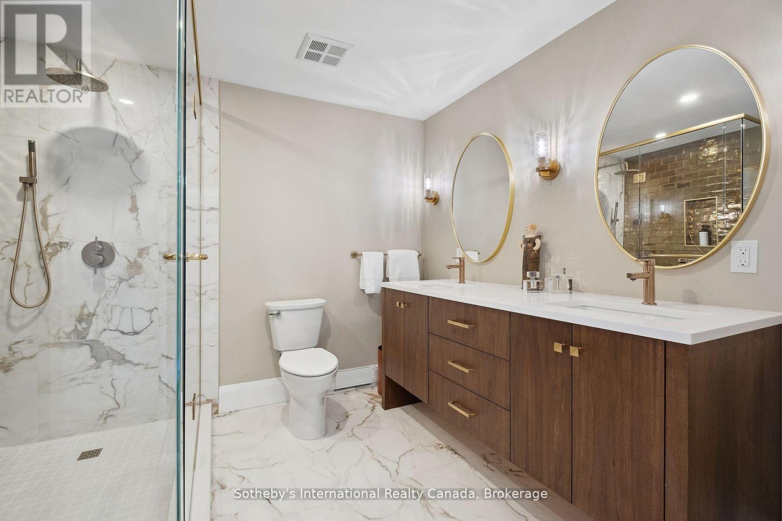 Modern bathroom with a marble walk-in shower and double-sink dark wood vanity.