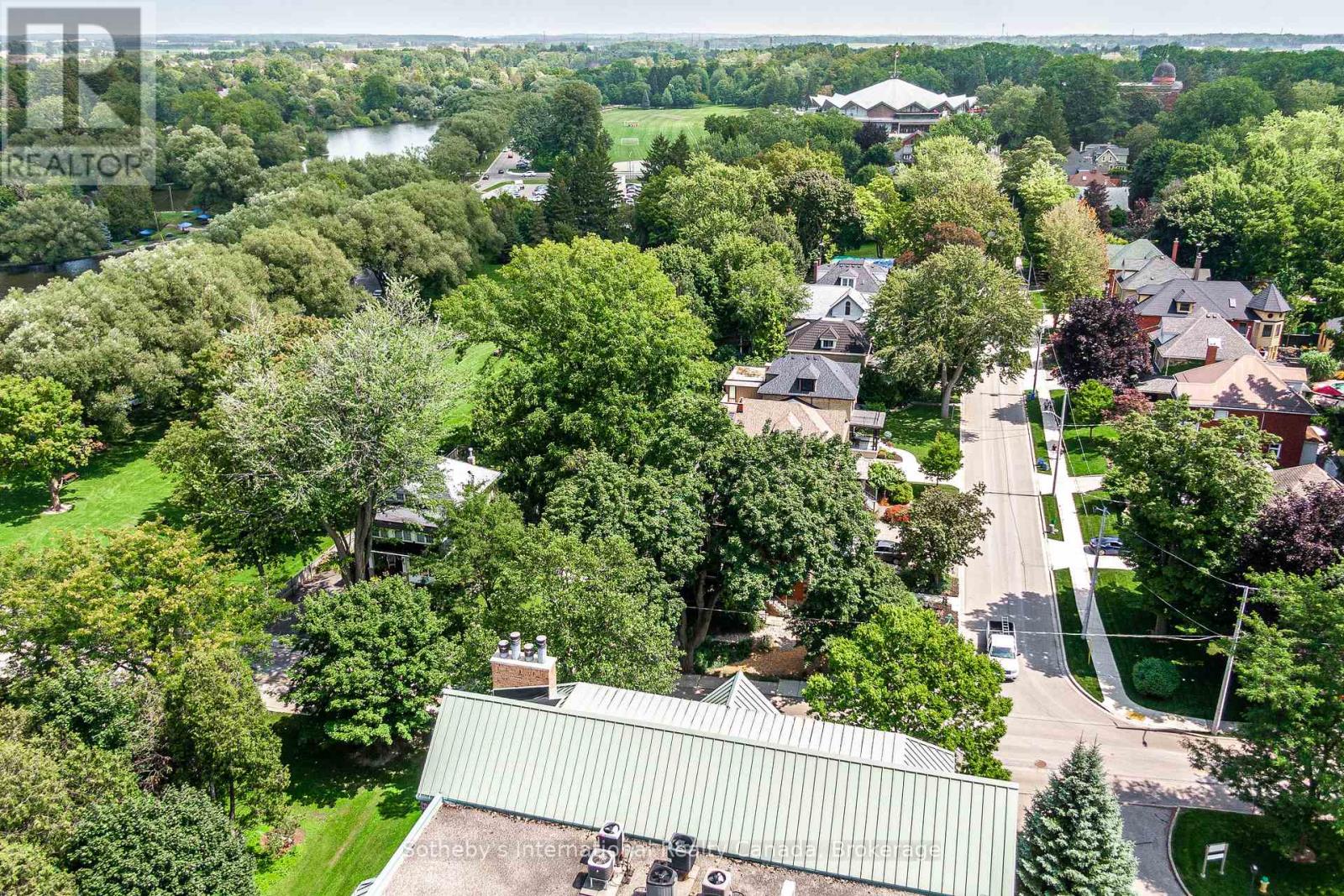 Aerial view of a leafy Stratford neighborhood, with a waterway and sports field in the distance.
