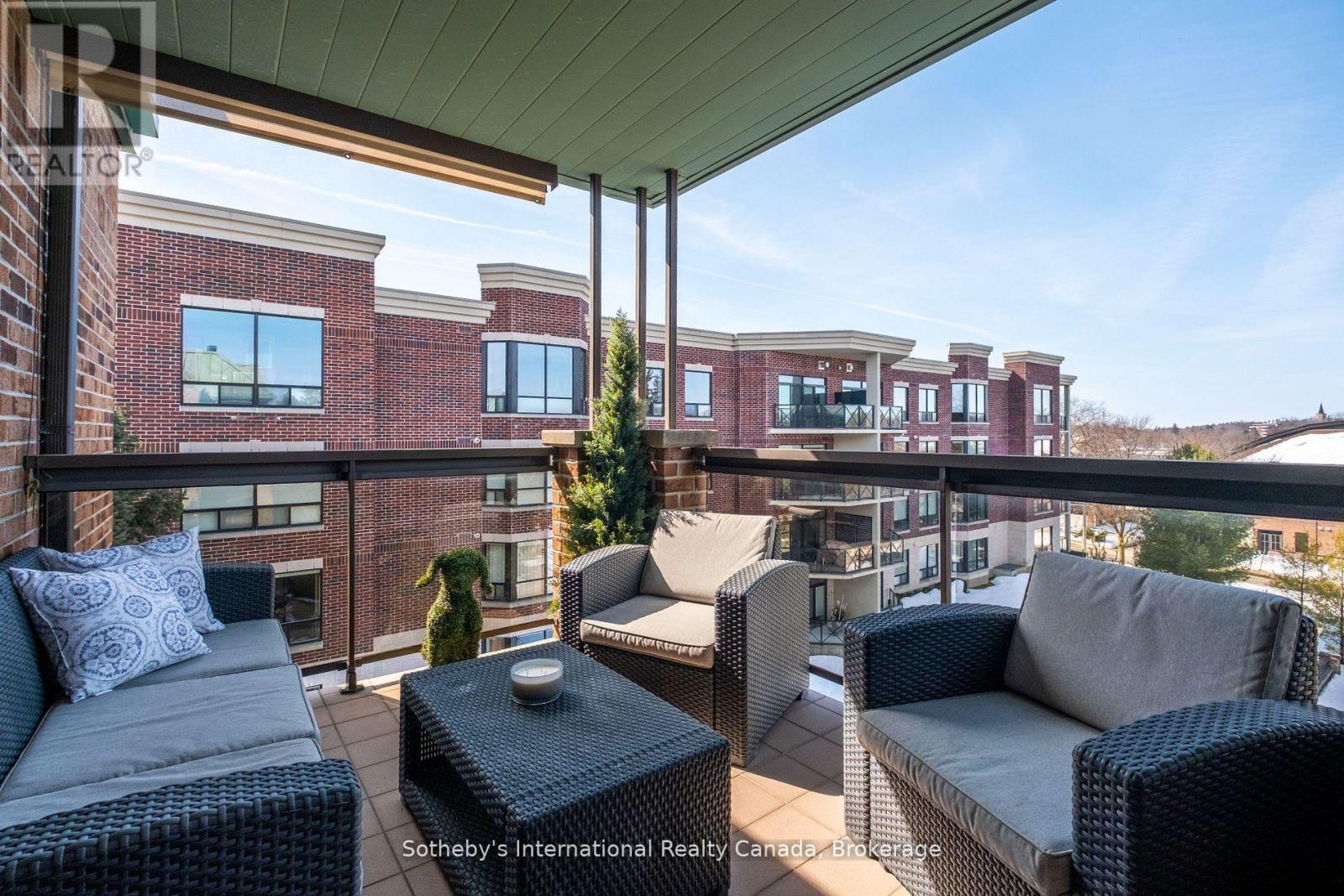 Furnished covered balcony with woven seating overlooking neighboring brick condominium buildings.