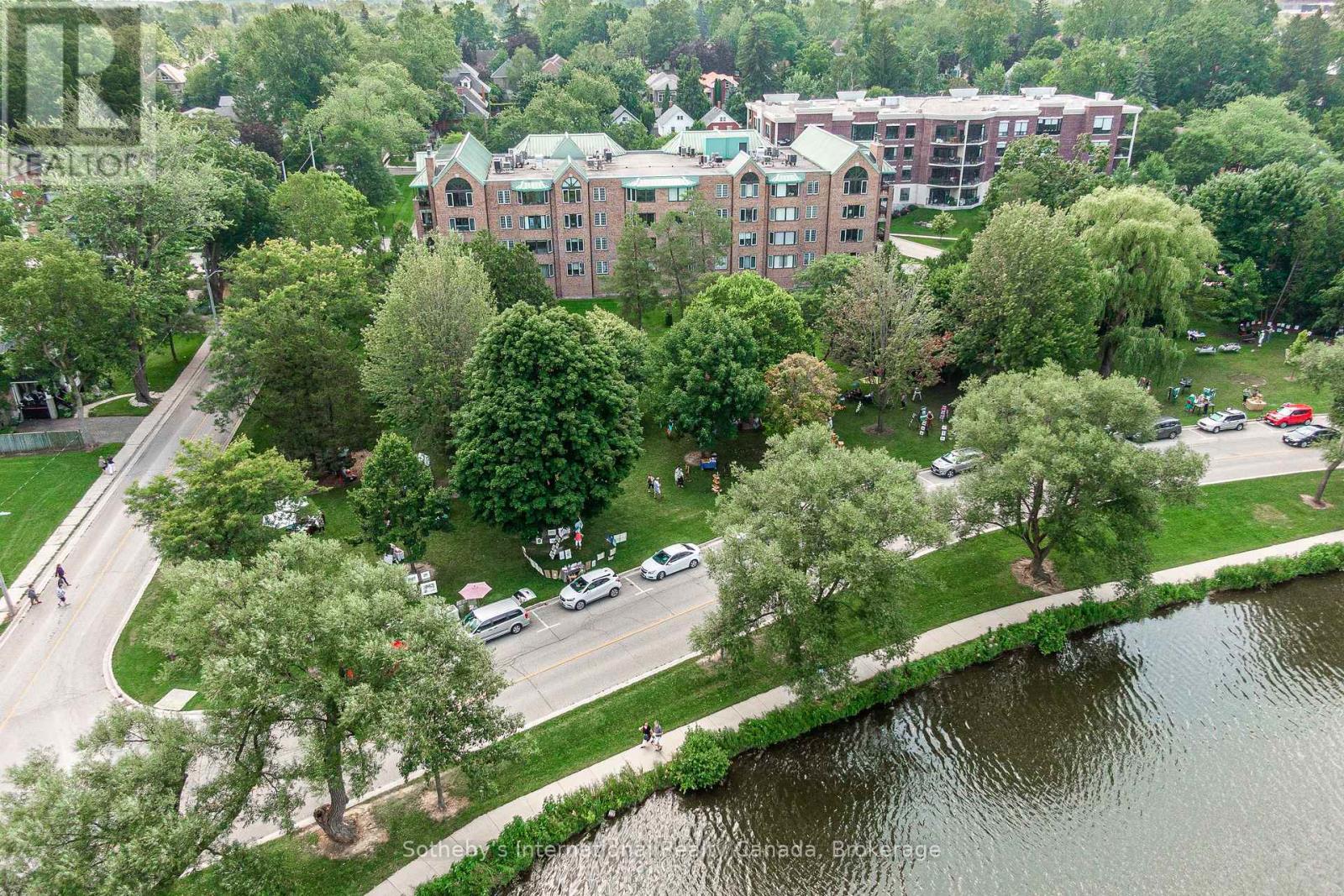 Aerial view of a brick apartment building beside a tree-lined river.