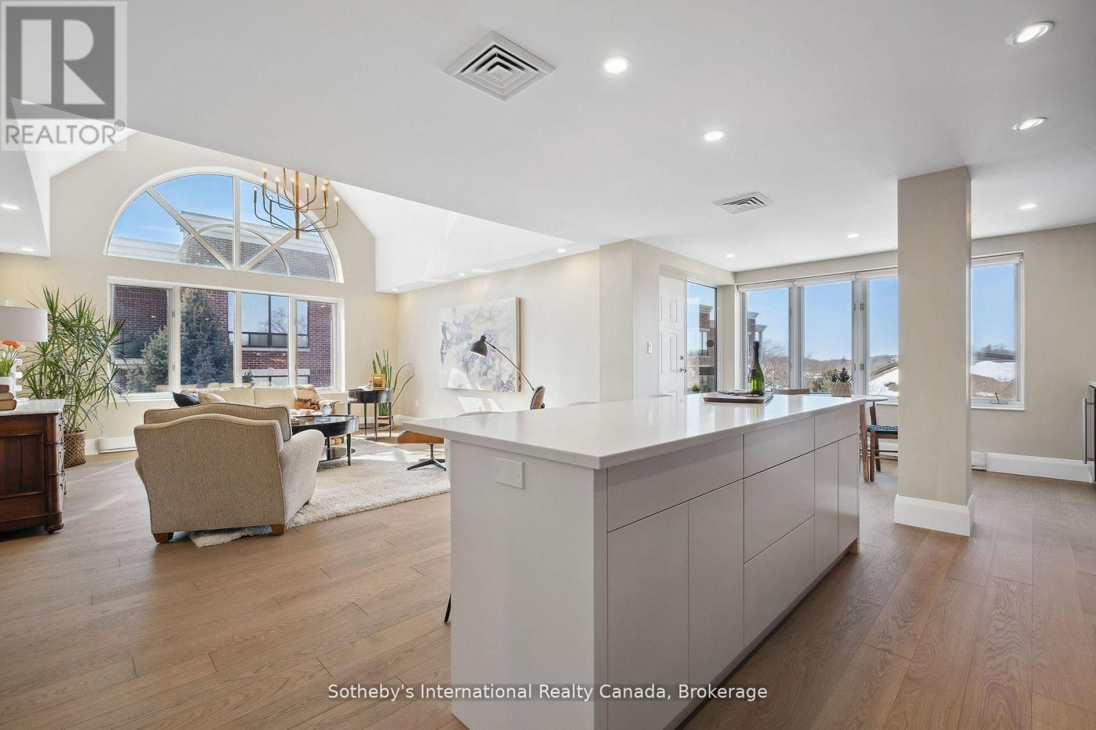 Open-plan condo kitchen and living area with a large island and arched windows.