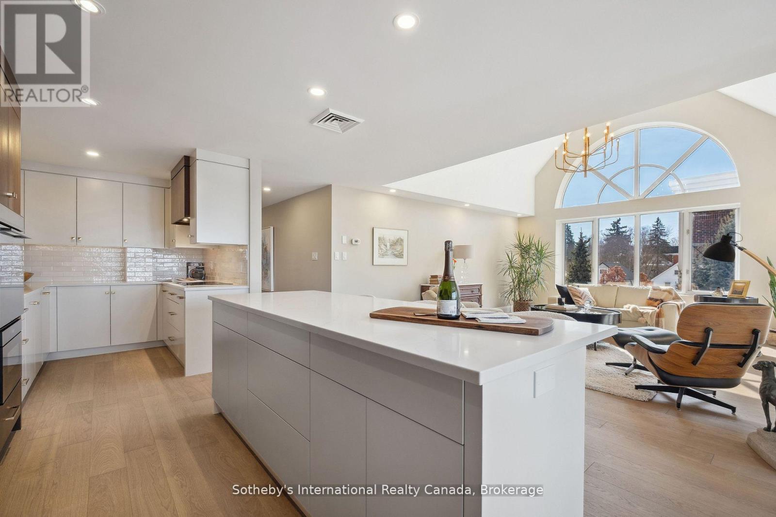 Open-plan kitchen and living area with a large island and vaulted ceiling with an arched window.