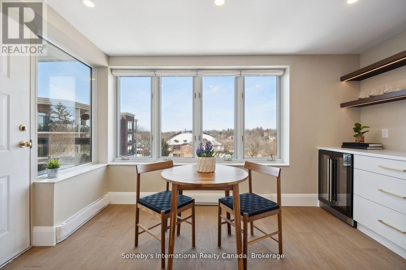Condo dining nook with a round table, corner windows, and views over snowy rooftops.