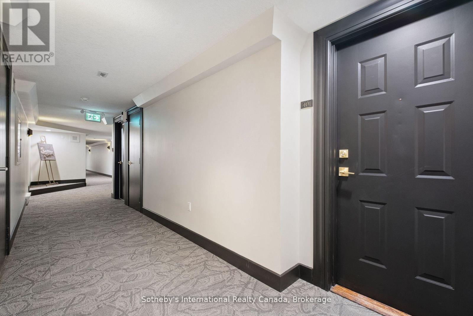 Condominium hallway leading to suite 401, with a dark paneled door and patterned gray carpet.