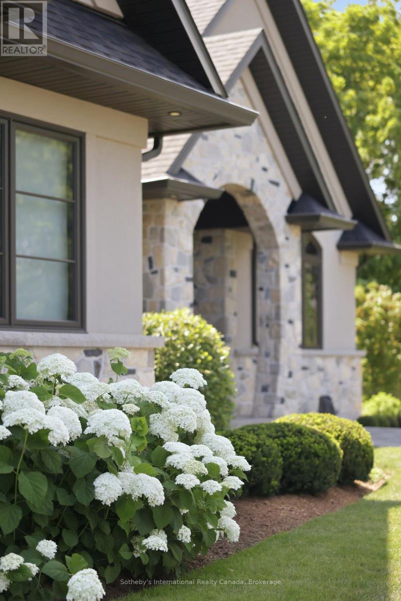 Stone house entrance with steep dark gables, an arched doorway, and white hydrangeas.