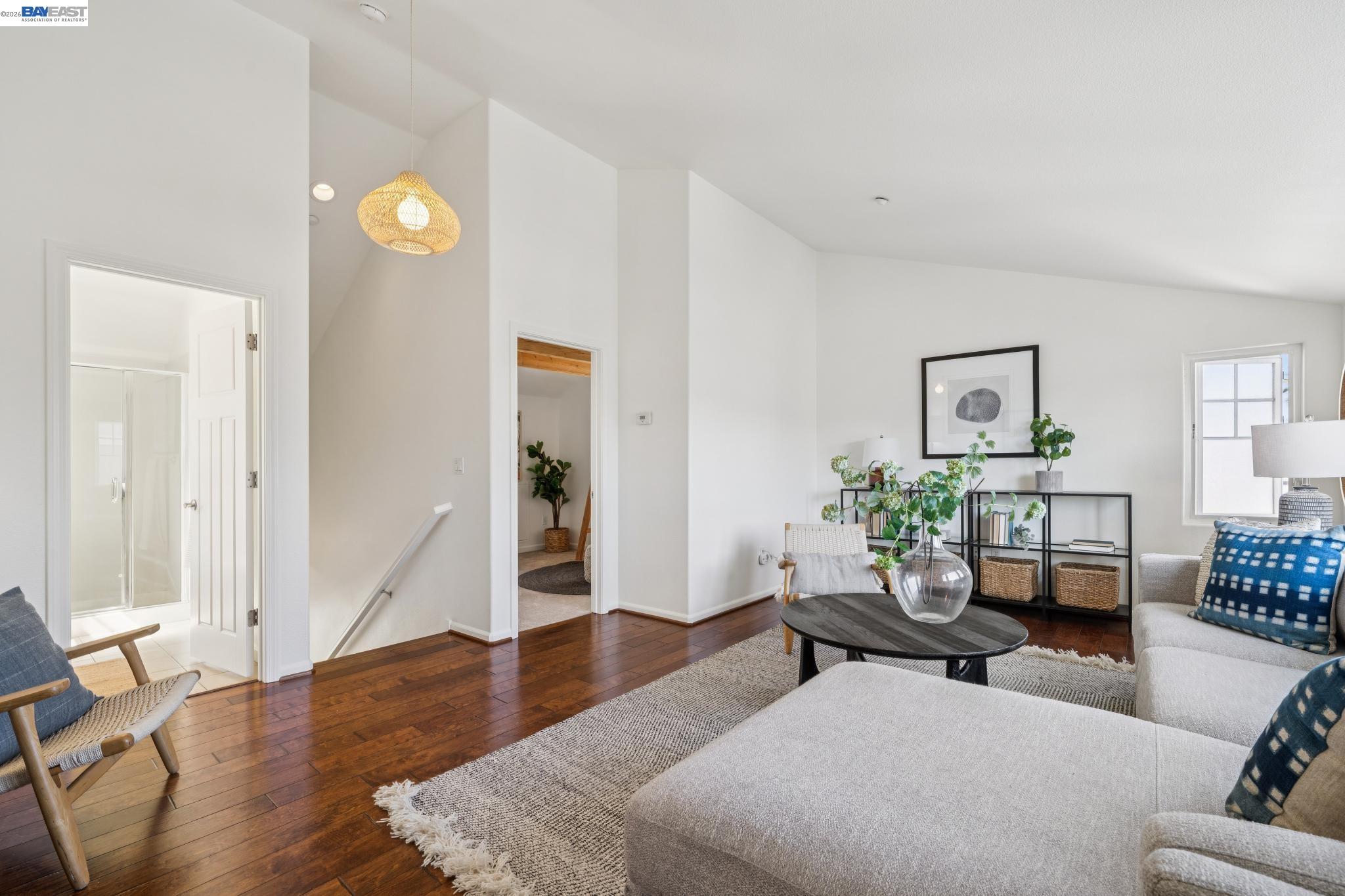 Staged living room with high ceilings, dark hardwood floors, and a gray sectional.
