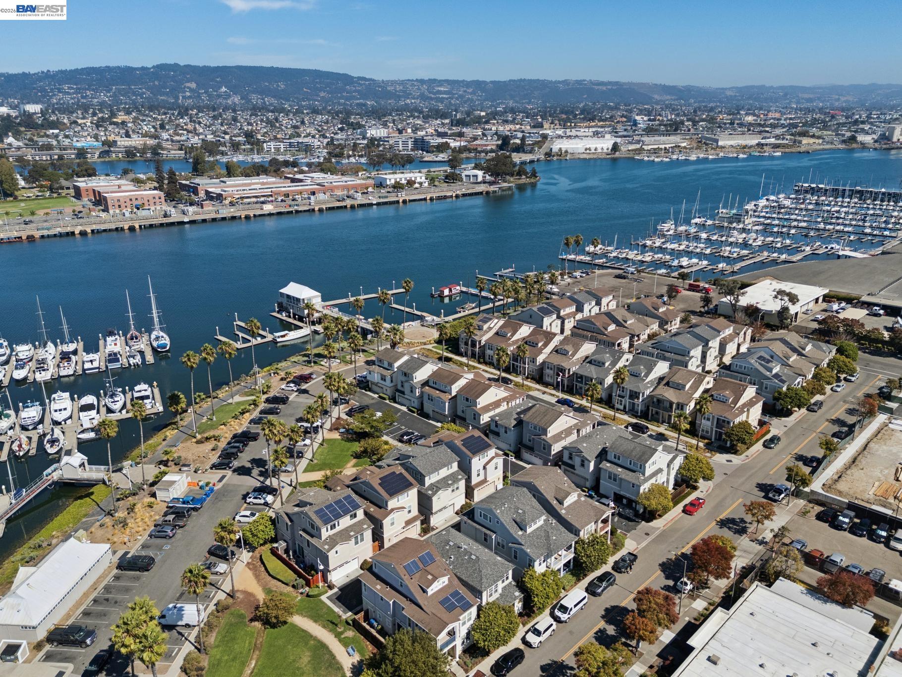 Aerial view of waterfront homes, marinas, and Alameda’s harbor on a clear day.