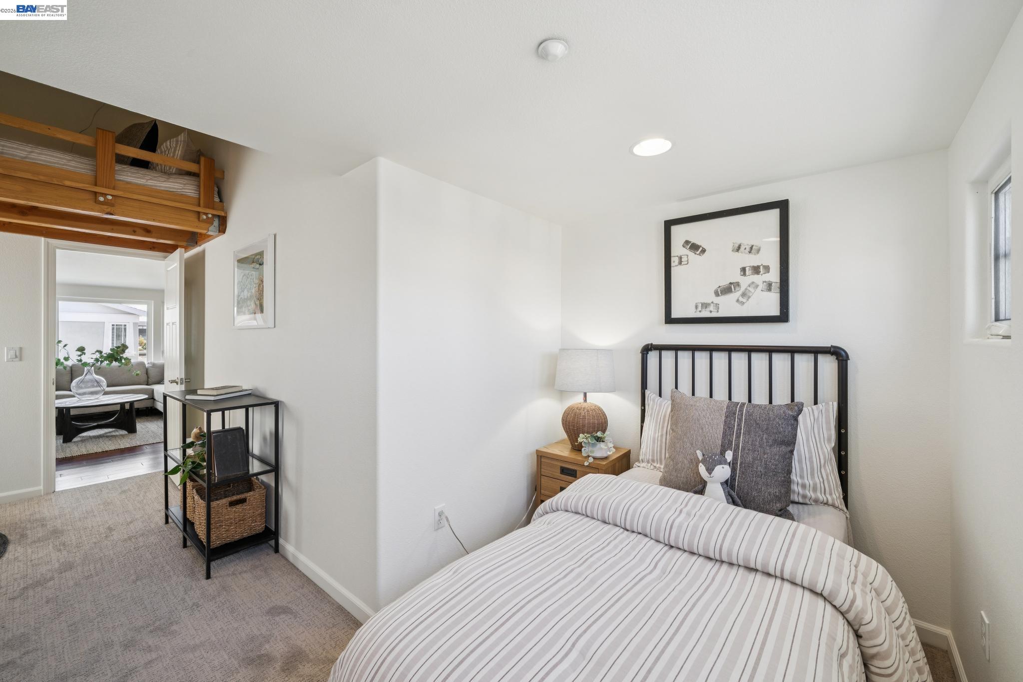 Bedroom with striped bedding beneath a wooden overhead loft bed.