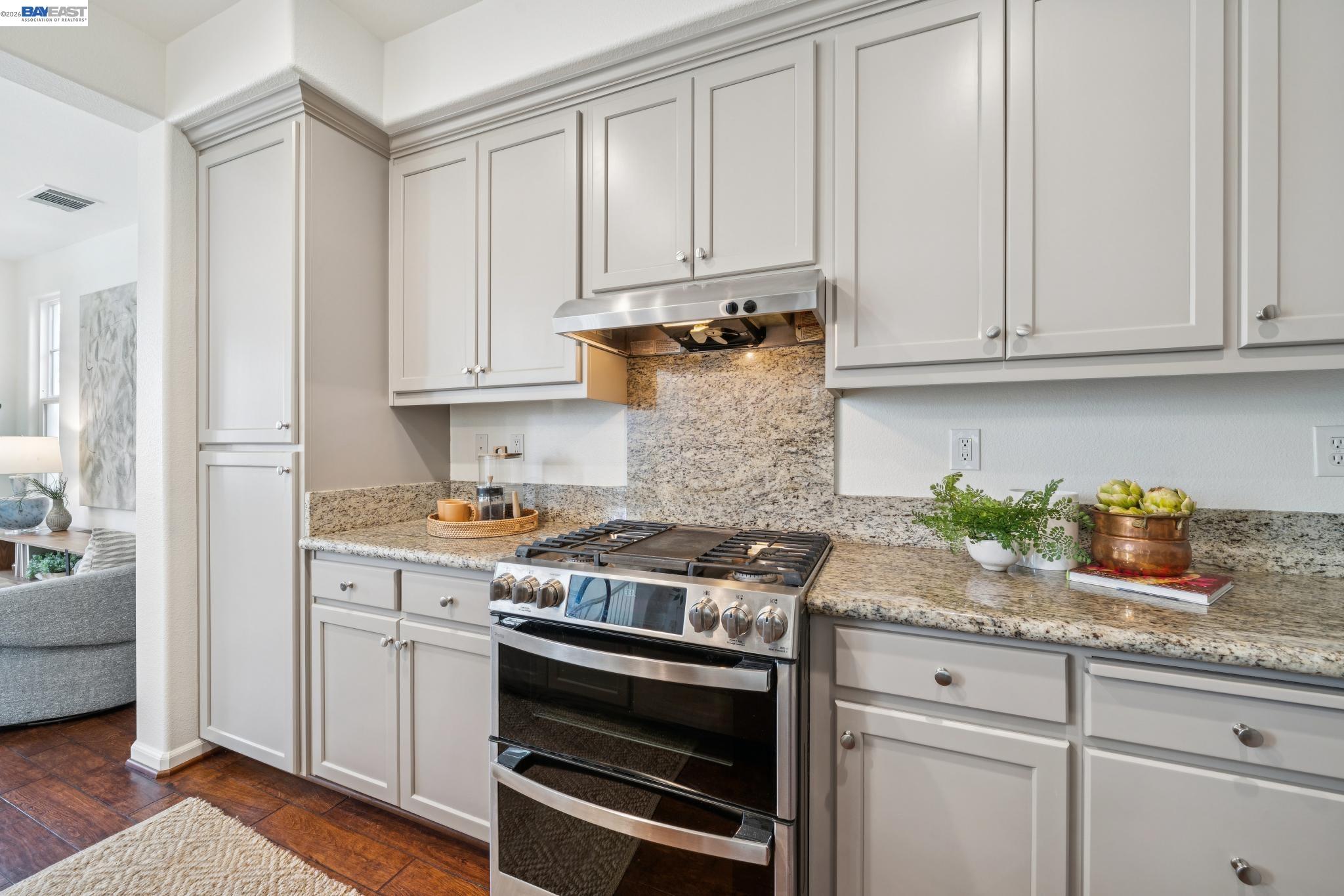 Kitchen with granite counters, light cabinetry, and a stainless-steel gas range.