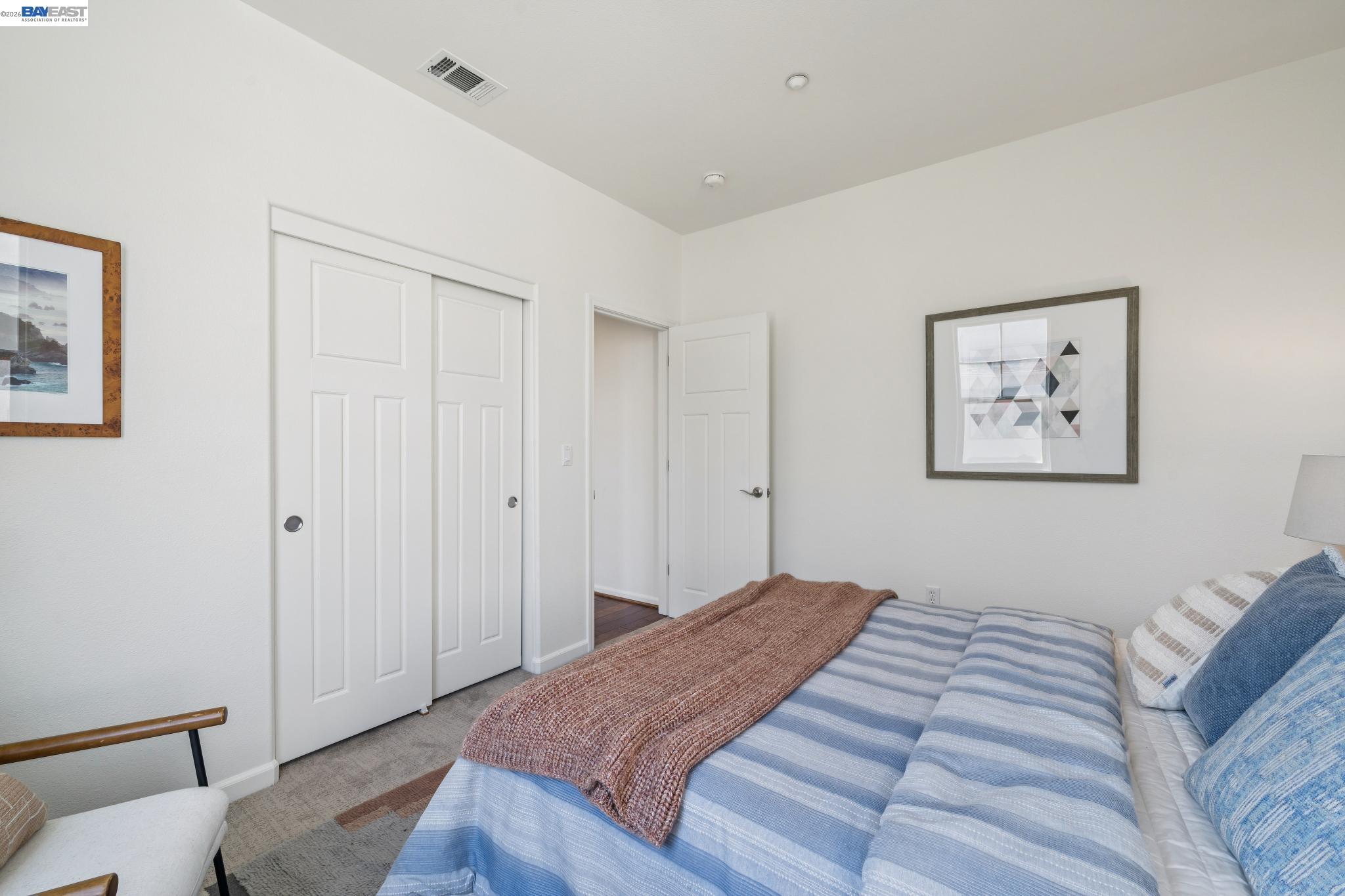 Bedroom with a blue-striped bed, brown knitted throw, and white closet doors.