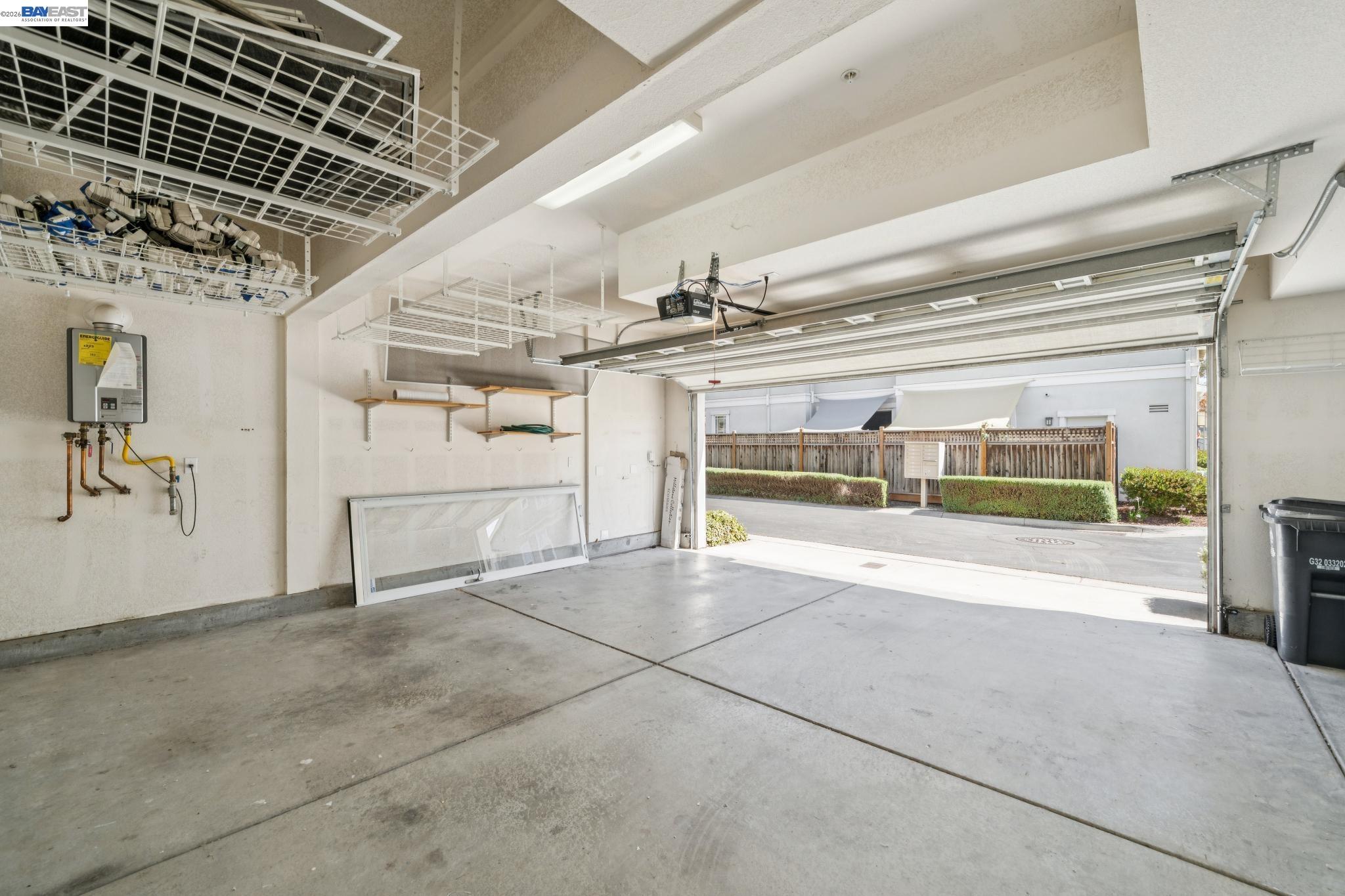 Garage with open overhead door, ceiling storage racks, and a wall-mounted water heater.