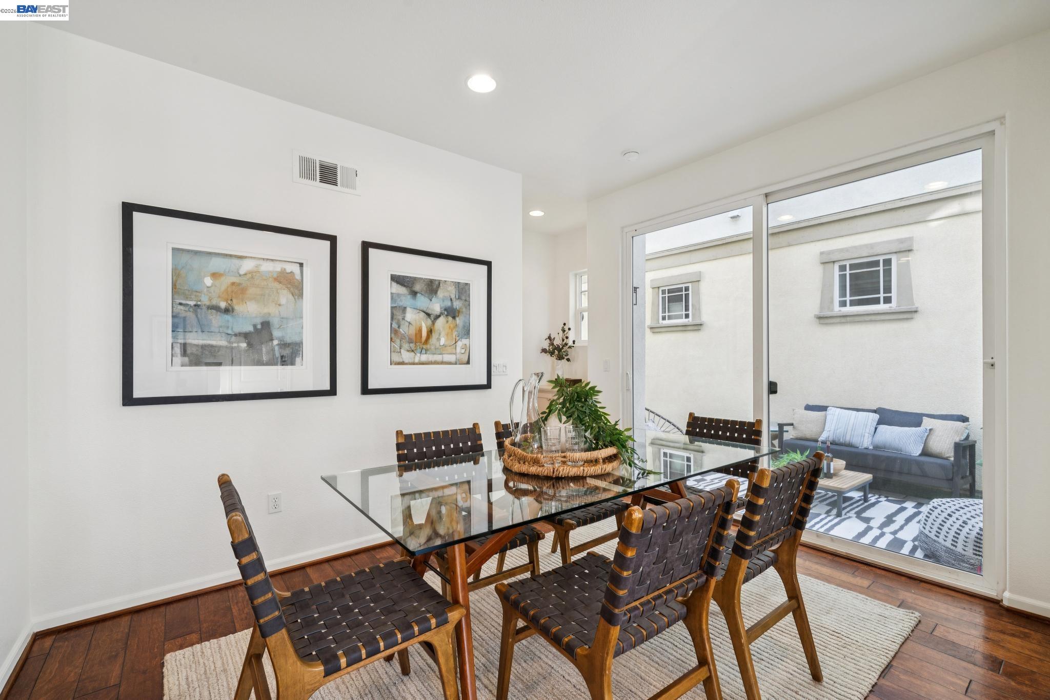 Dining room with a glass-top table, woven chairs, and sliding doors to a furnished patio.