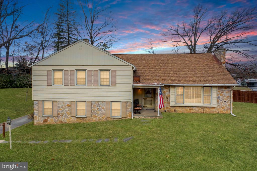 Two-story home with stone accents, a covered entry, and a broad lawn at dusk.