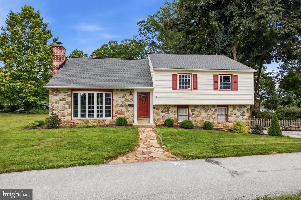 Split-level house with a stone facade, red shutters, and a stone walkway to the front door.