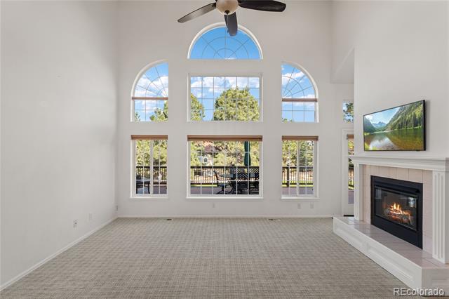 Living room with tall arched windows, a fireplace, and a television above it.