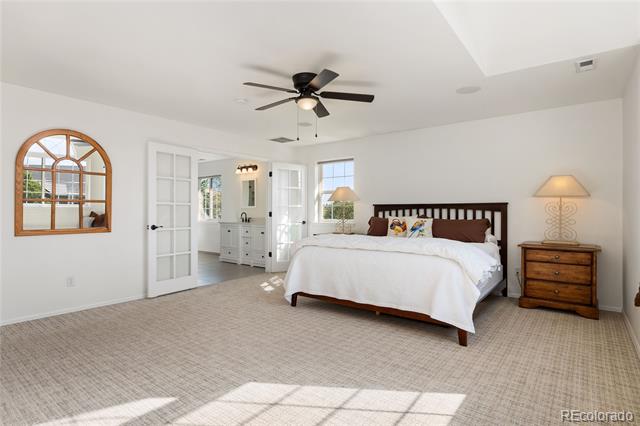 Bright bedroom with a dark wood bed, white bedding, and sunlight across the carpet.