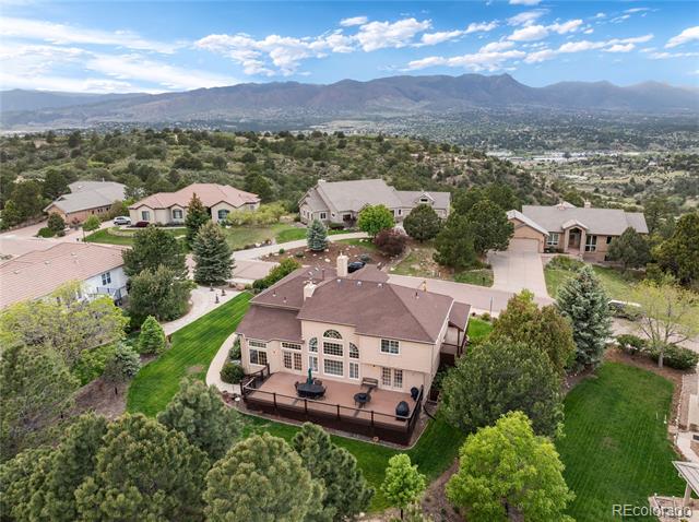 Aerial view of a tan home with a deck and mountain backdrop.