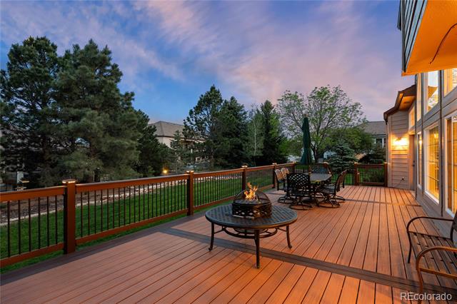 Spacious wooden deck with outdoor furniture and a fire pit at dusk.