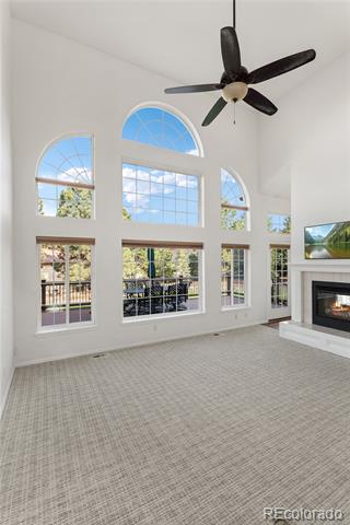 Unfurnished living room with tall arched windows, beige carpet, and a fireplace.