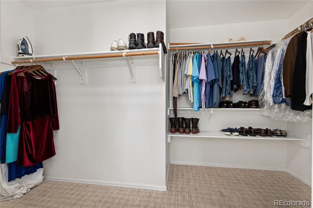 Walk-in closet with clothes and shoes arranged on rods and shelves.