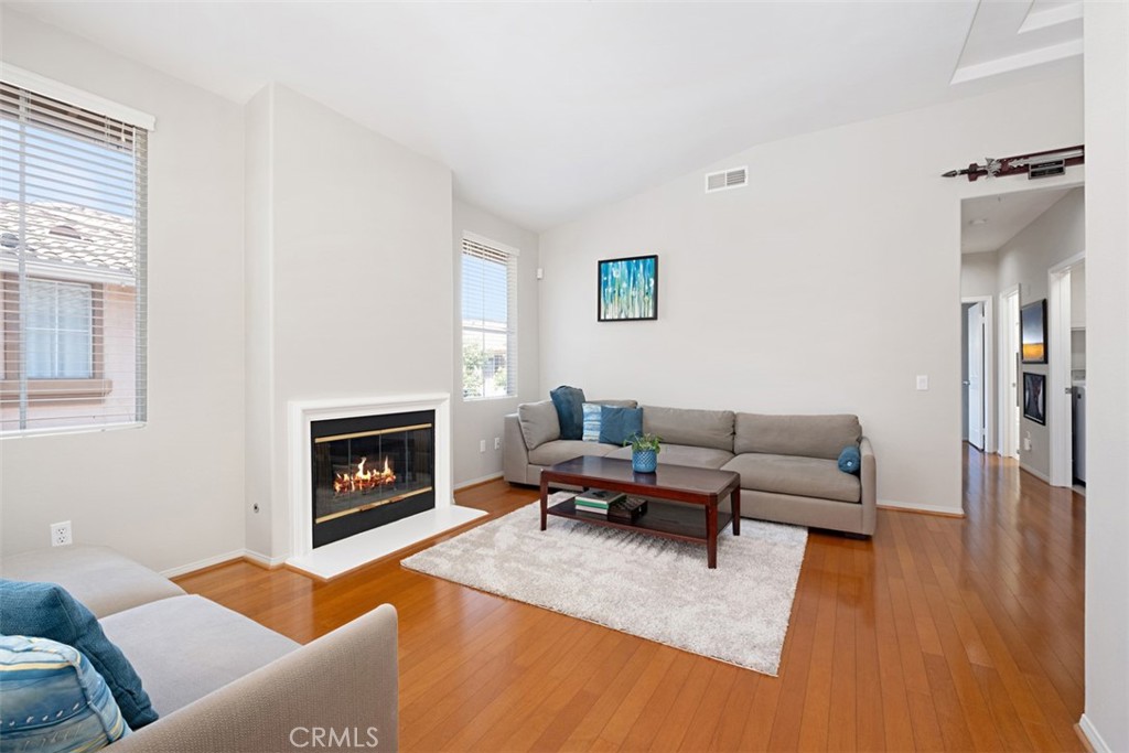 Living room with a gas fireplace, gray sectional sofas, and warm hardwood floors.